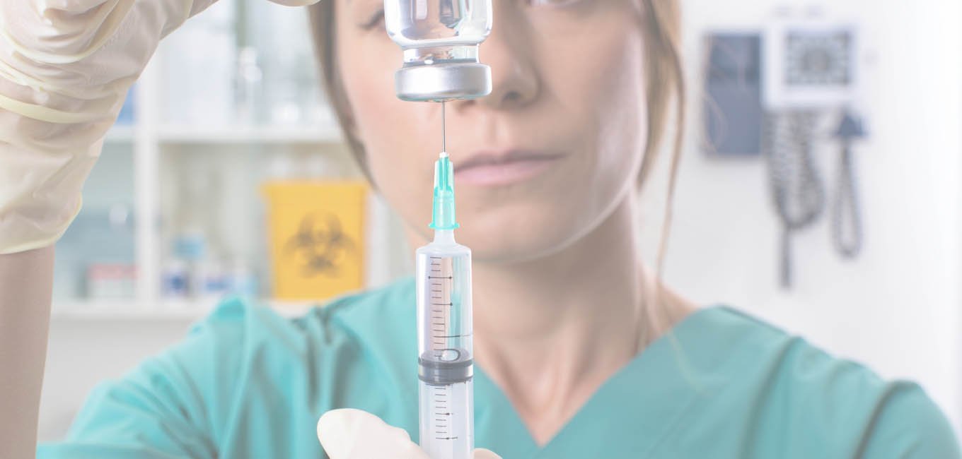 Медицинская работница уверенно подготавливает шприц с лекарством